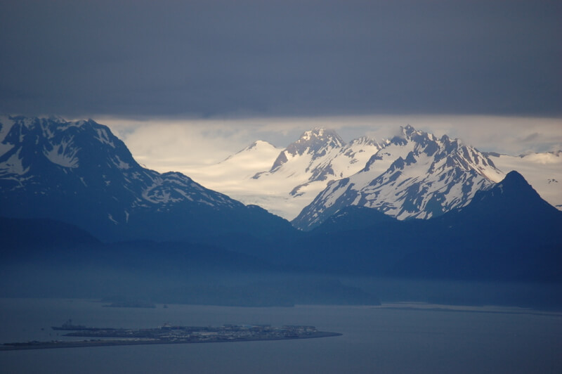 Day 20 We approach Homer Spit. From the elevation of the road, we see the strip of land bowing into the sea in front of imposing mountains with glacial ravines of unfathomable scale.