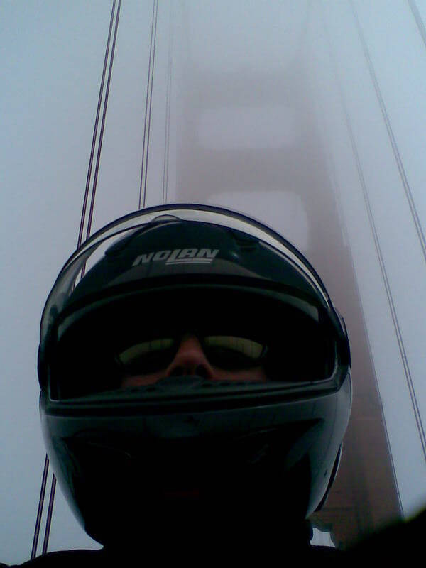 Day 33 I cross the red oxide bridge, the uprights disappearing into the mist, but it doesn’t stop me from taking photos of myself with them in the background, my jacket half unzipped and the ‘h’ of my Motorhead T-shirt visible beneath my bandana.